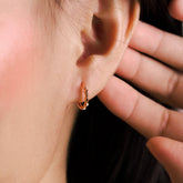 Fine jewellery, silver jewellery plated with rose gold, hypoallergenic, tarnish-free, Close-up front view of an ear with a rose gold hoop earring, hand holding the earlobe.
